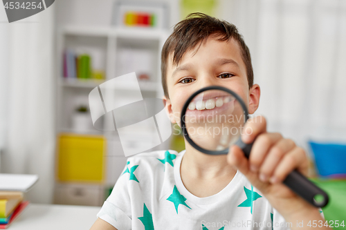 Image of boy with magnifier showing big teeth at home