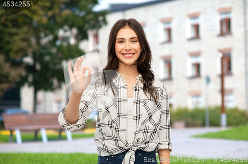 Image of teenage girl showing ok hand sign over campus