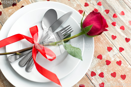 Image of close up of red rose flower on set of dishes