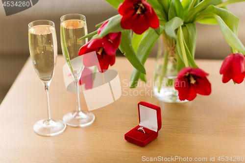 Image of diamond ring, champagne and flowers on table