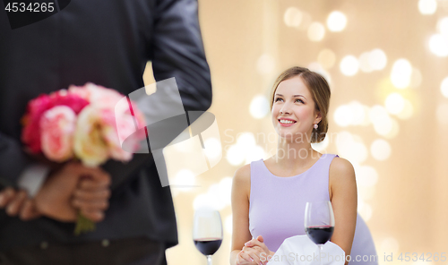 Image of young woman looking at man with flower bouquet