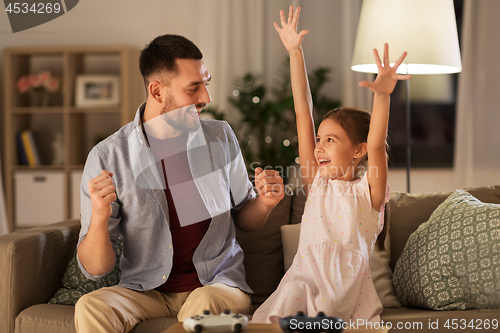 Image of father and daughter playing video game at home