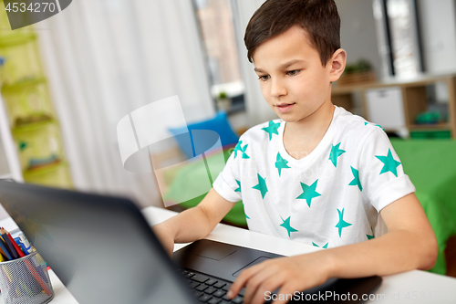 Image of student boy typing on laptop computer at home