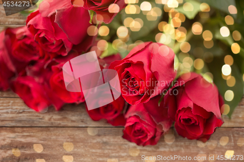 Image of close up of red roses bunch over festive lights