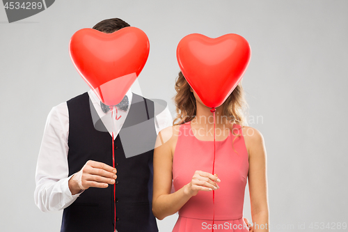 Image of couple hiding behind red heart shaped balloons