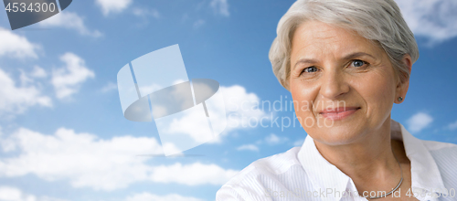 Image of portrait of smiling senior woman over blue sky