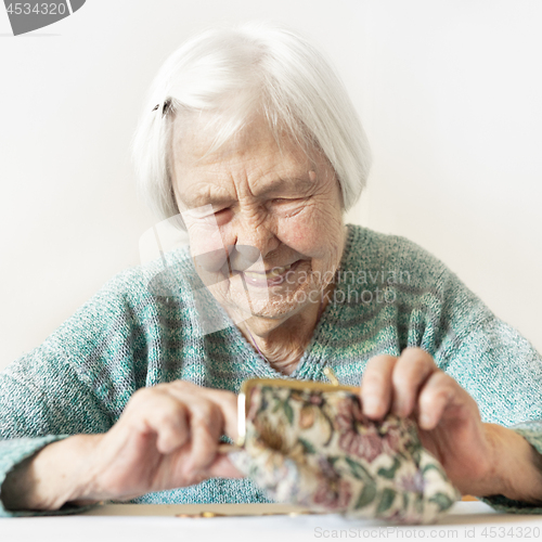 Image of Cheerful elderly 96 years old woman sitting at table at home happy with her pension savings in her wallet after paying bills.