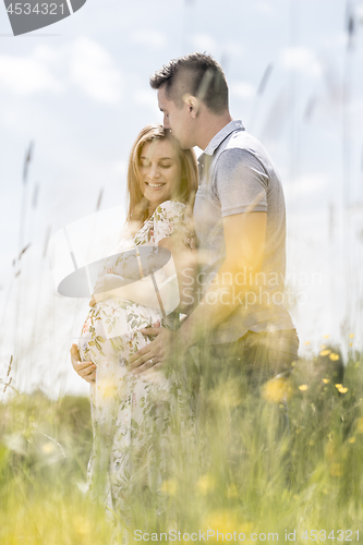 Image of Young happy pregnant couple hugging in nature.