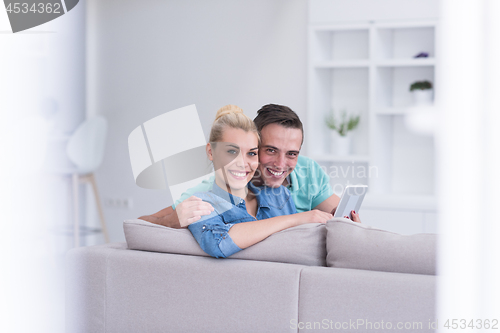 Image of couple relaxing at  home with tablet computers