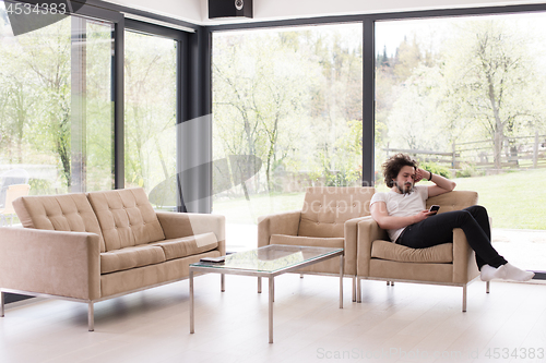 Image of young man using a mobile phone  at home