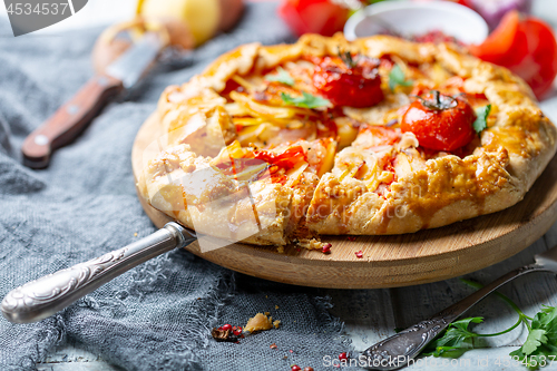 Image of Open pie with potatoes, bacon and tomatoes.