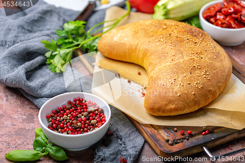 Image of Homemade pizza calzone on a wooden board.