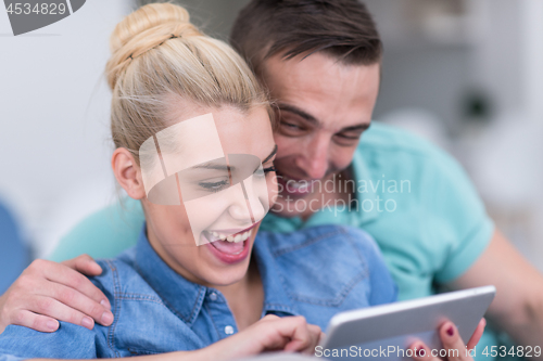 Image of couple relaxing at  home with tablet computers