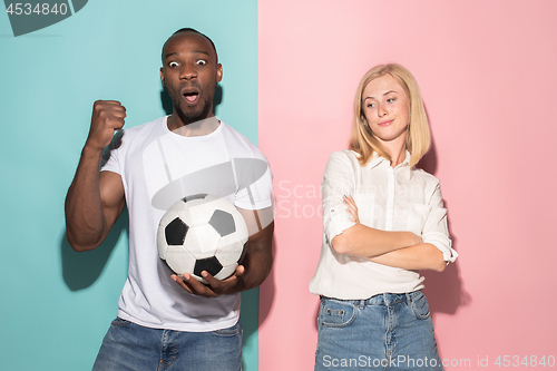 Image of Closeup portrait of young couple, man, woman. One being excited happy smiling, other serious, concerned, unhappy on pink and blue background. Emotion contrasts