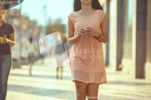 Image of Beautiful woman holding paper coffee cup and enjoying the walk in the city