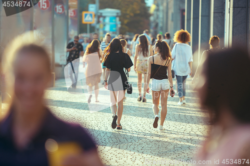 Image of Beautiful woman holding paper coffee cup and enjoying the walk in the city