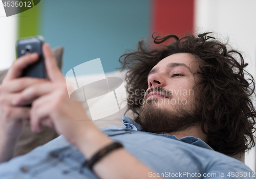 Image of young man using a mobile phone  at home