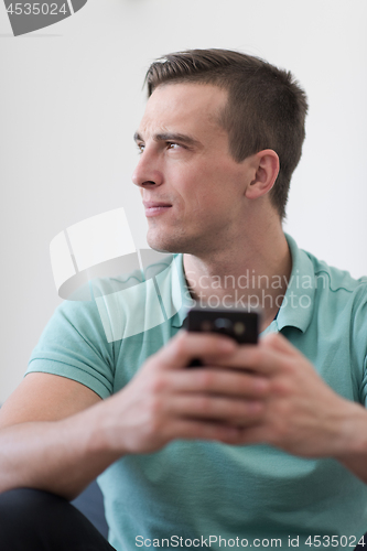 Image of young man using a mobile phone  at home