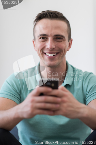 Image of young man using a mobile phone  at home