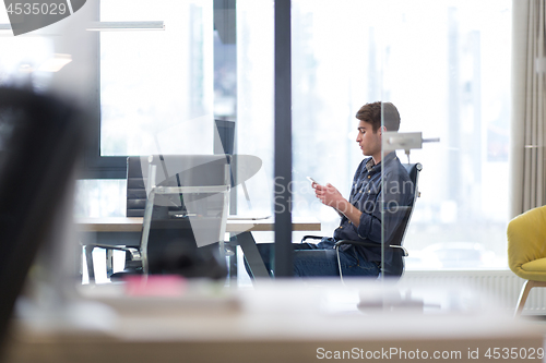 Image of Young casual businessman using smartphone