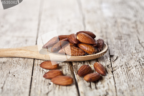 Image of Organic fresh almond seeds on wooden spoon closeup on rustic woo