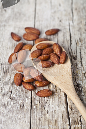 Image of Fresh raw almond seeds on wooden spoon closeup on rustic wooden 