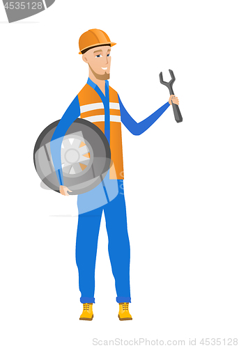 Image of Young caucasian mechanic with tyre and spanner.