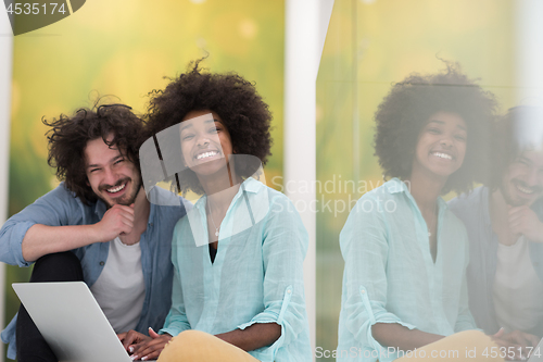 Image of multiethnic couple using a laptop on the floor