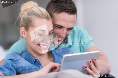 Image of couple relaxing at  home with tablet computers