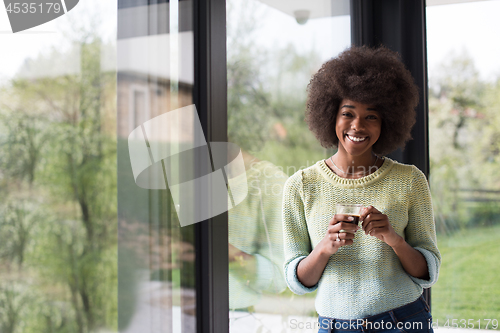 Image of African American woman drinking coffee looking out the window