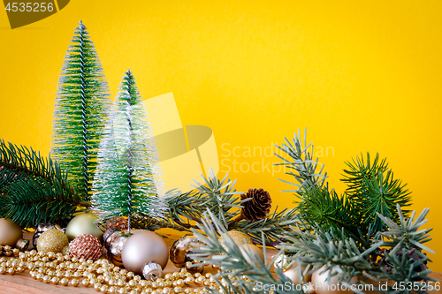 Image of Christmas decoration glass balls with fir trees on yellow backgr