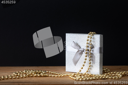 Image of Holidays decoration gift box with golden perls on black backgrou