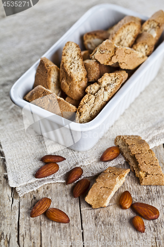 Image of Cookies cantuccini in white ceramic bowl and almond seeds on lin