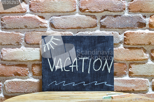 Image of Chalk board with the word VACATION drown by hand and chalks on w