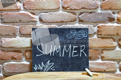 Image of Chalk board with the word SUMMER drown by hand and chalks on woo