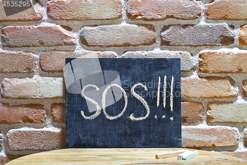 Image of Chalk board with the word SOS! drown by hand and chalks on woode