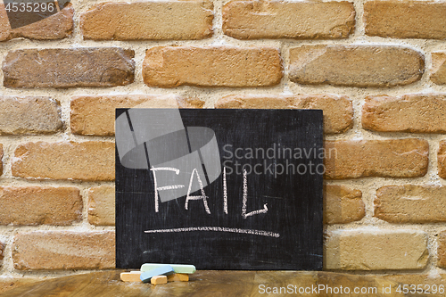 Image of Chalk board with the word FAIL drown by hand and chalks on woode