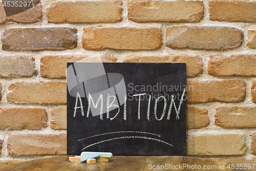 Image of Chalk board with the word AMBITION drown by hand and chalks on w