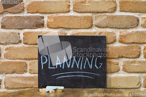 Image of Chalk board with the word PLANNING drown by hand and chalks on w