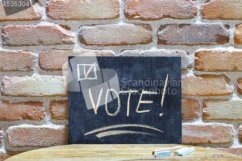 Image of Chalk board with the word VOTE! drown by hand and chalks on wood