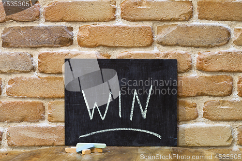 Image of Chalk board with the word WIN drown by hand and chalks on wooden