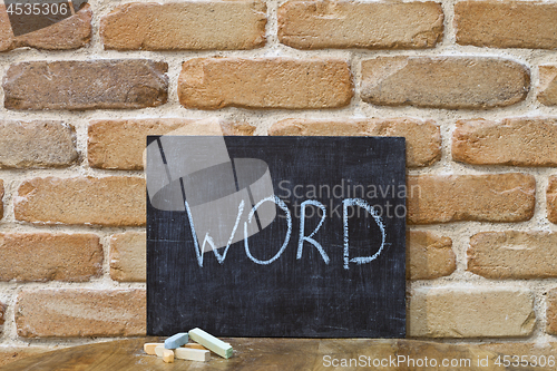 Image of Chalk board with the word WORD drown by hand and chalks on woode