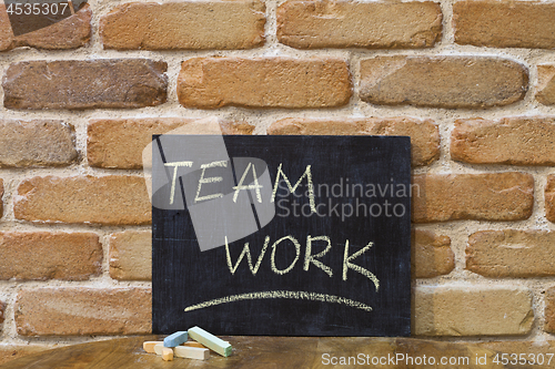 Image of Chalk board with the word TEAMWORK drown by hand and chalks on w