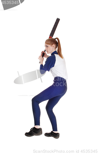 Image of Woman swinging her bat in softball leg up