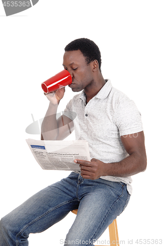 Image of African man drinking coffee, reading the paper