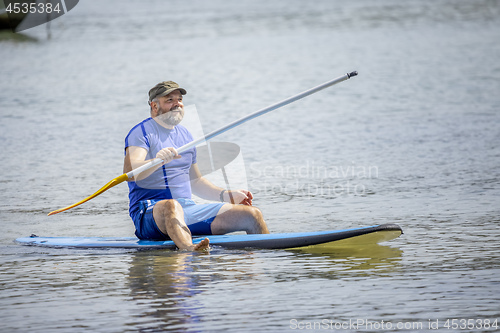 Image of a bearded man paddling in the ocean