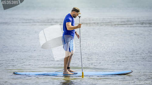 Image of a bearded man paddling in the ocean