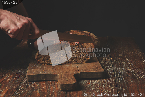 Image of Hands cutting rye bread