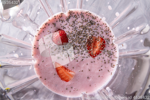 Image of Preparation of milkshake from milk, strawberries and chia seeds in a bowl of a blender, top view