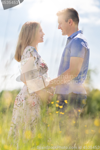 Image of Young happy pregnant couple hugging in nature.